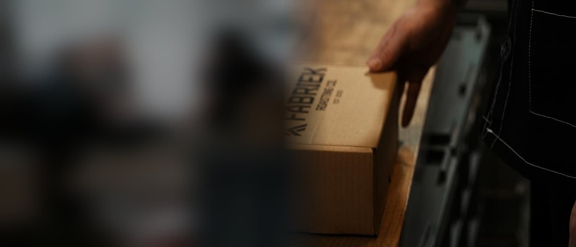 A hand on a FABRIEK Roasting Co. box, ready to leave